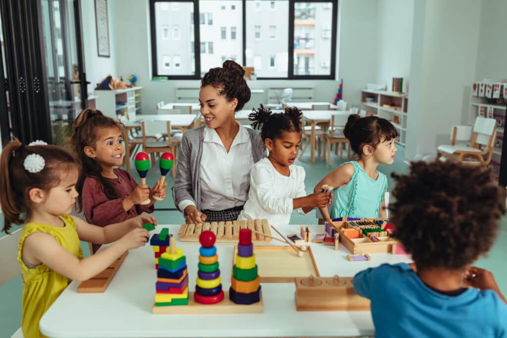 Teacher and children playing with toys in Kindergarten.